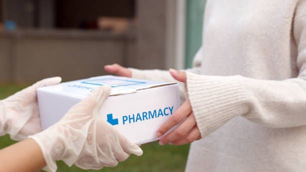 A person wearing gloves is holding a box that says pharmacy.