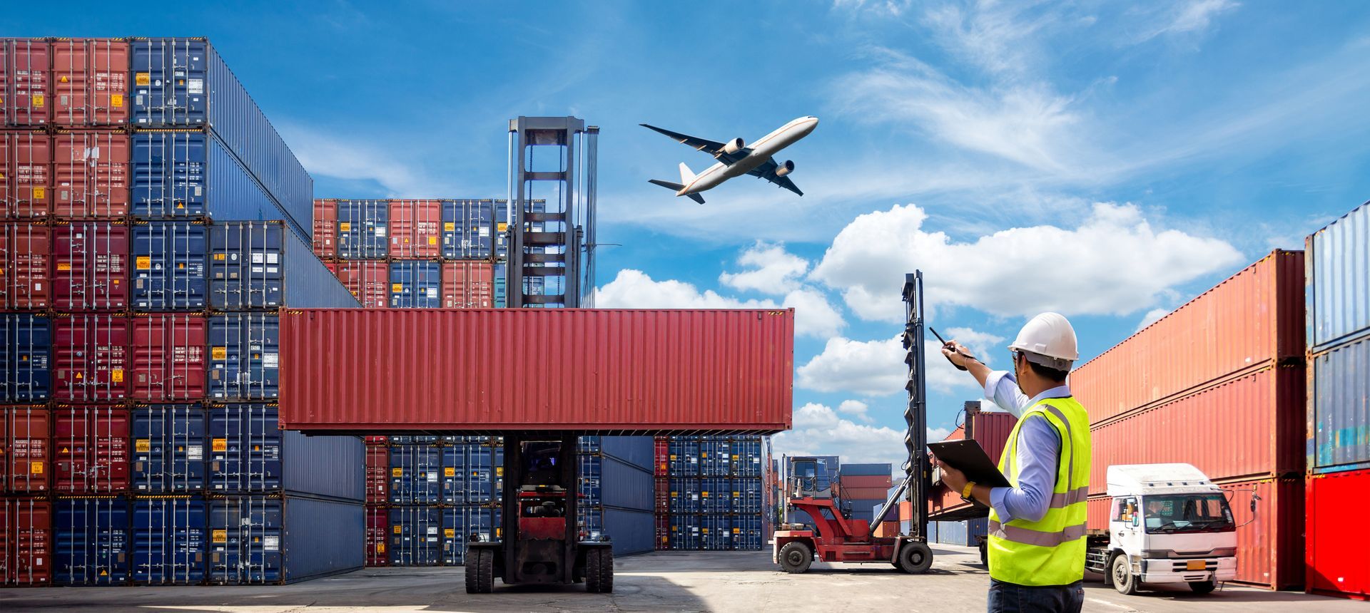 A man is standing in a warehouse looking at a plane flying overhead.