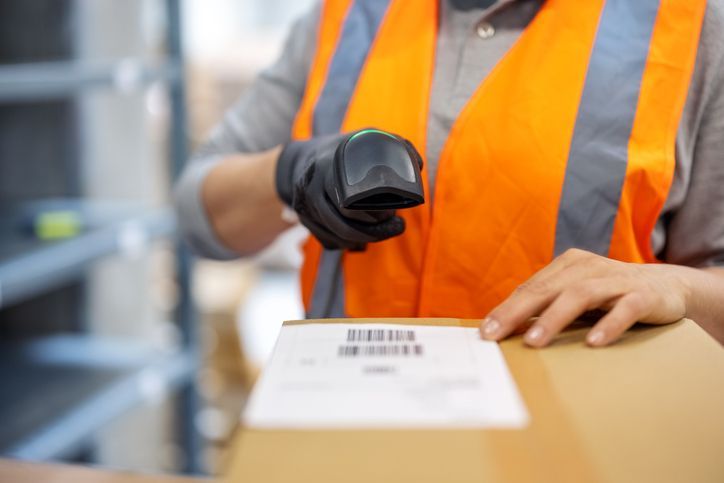 A warehouse worker is scanning a box with a barcode reader.