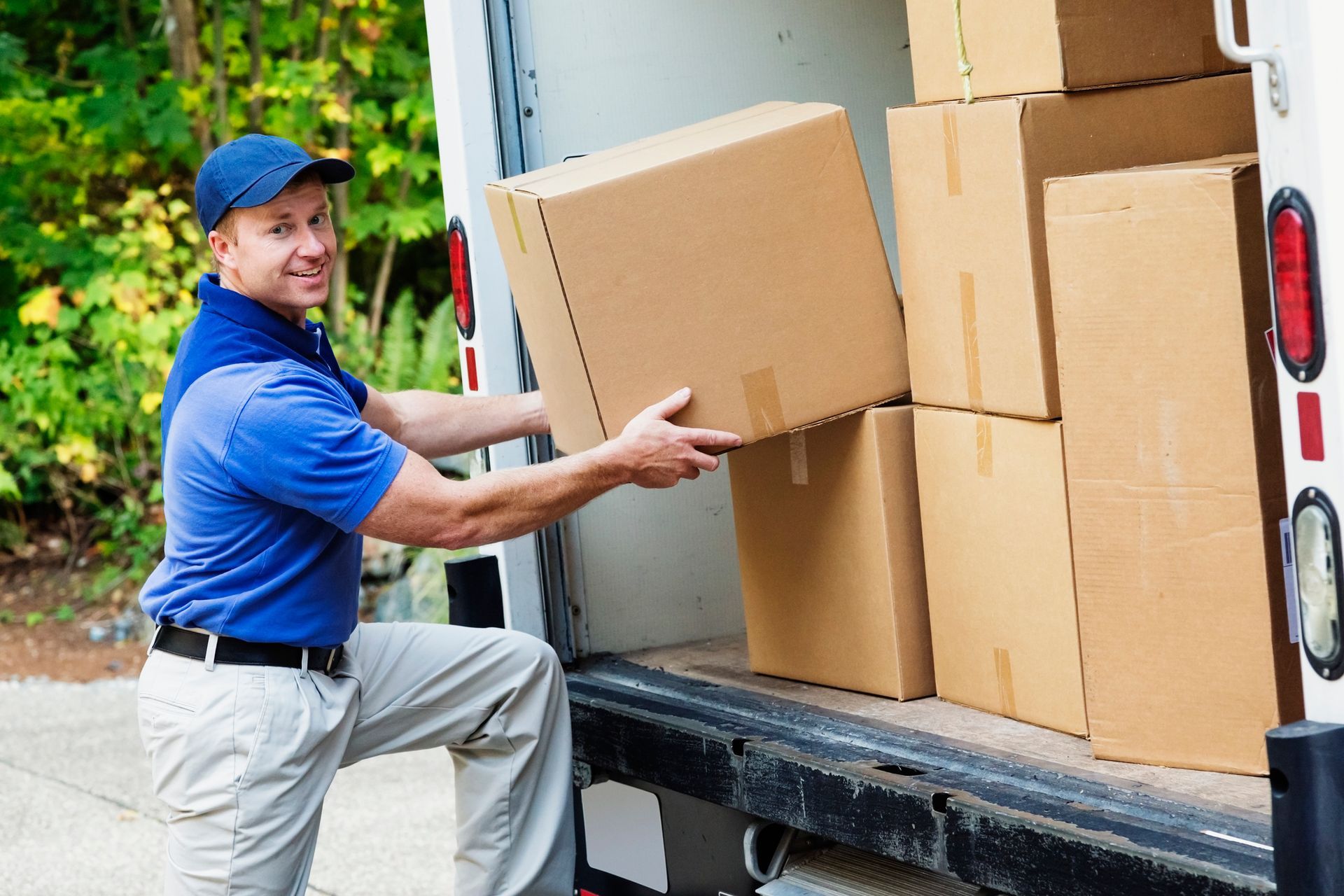 A delivery man is loading boxes into a truck.