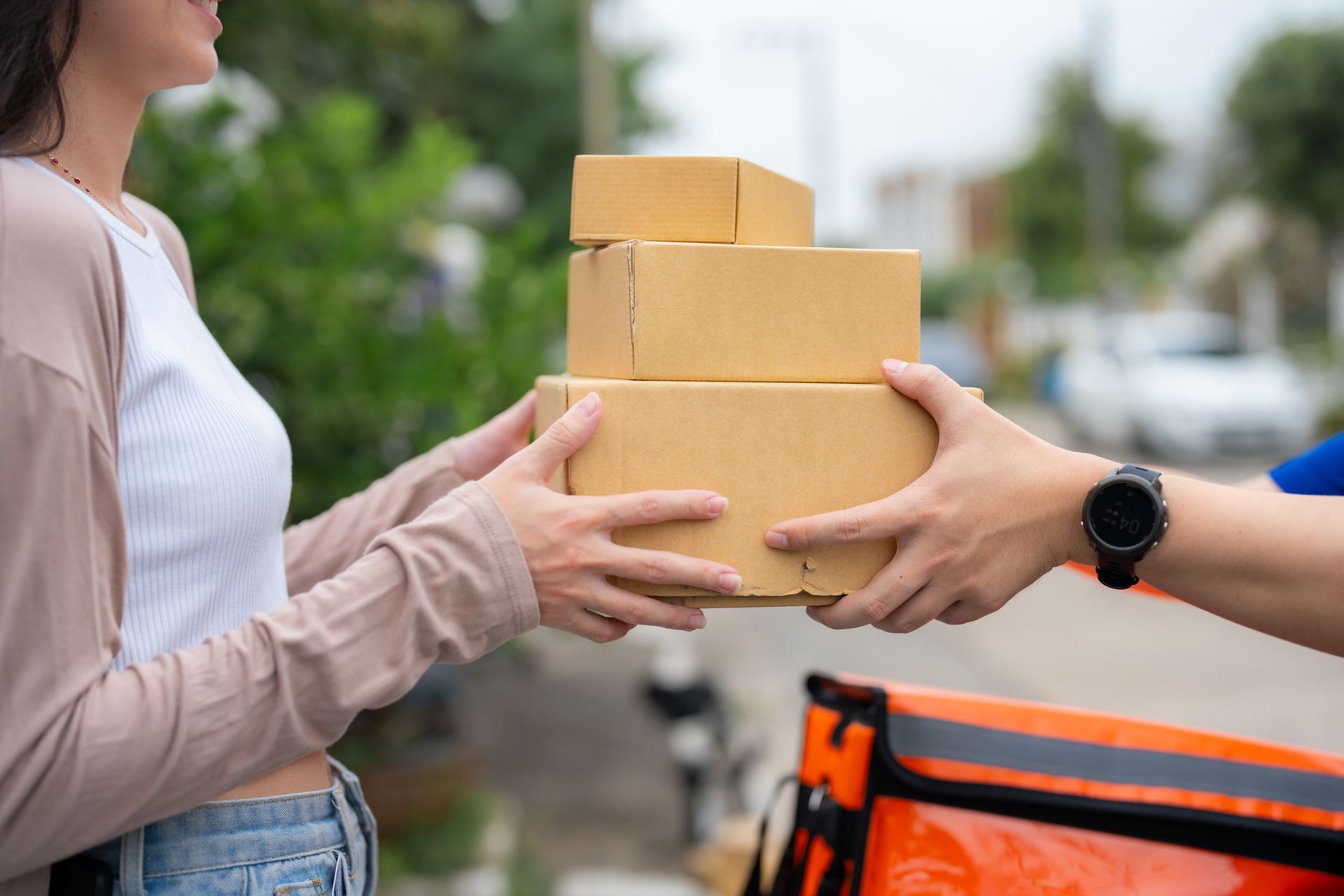 A woman is receiving a stack of boxes from a delivery man.