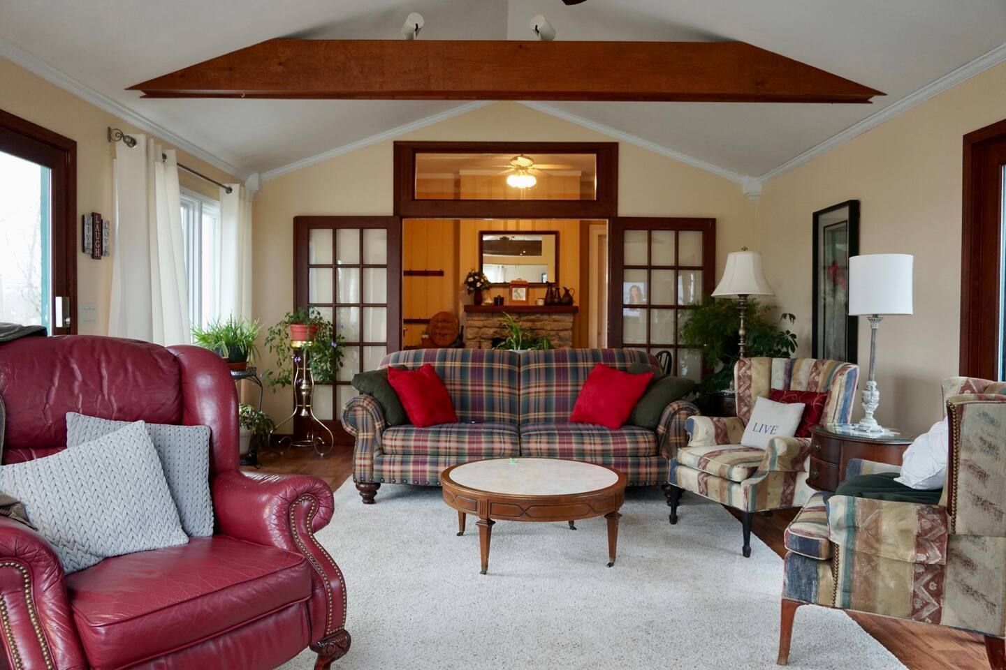 A living room with a plaid couch and red chairs