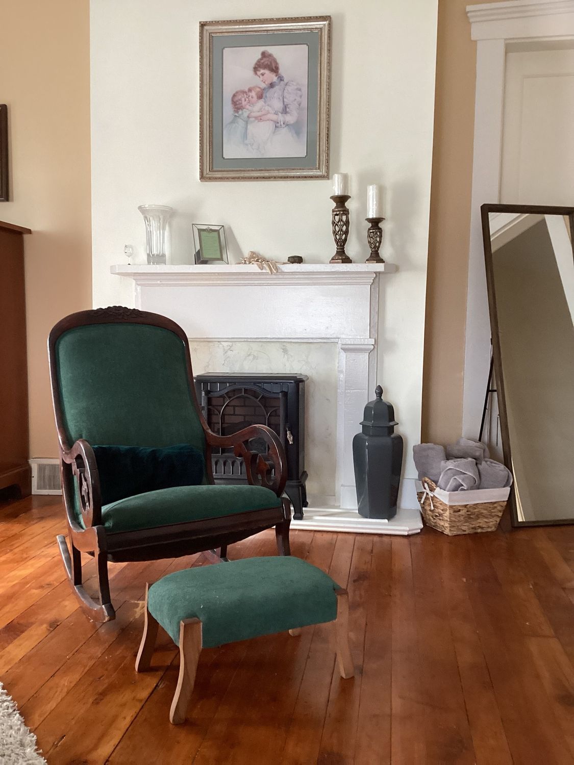A living room with a rocking chair and ottoman in front of a fireplace.
