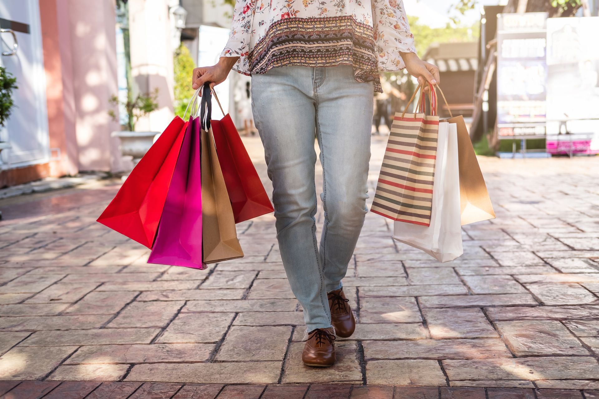 A woman is walking down a sidewalk holding shopping bags.