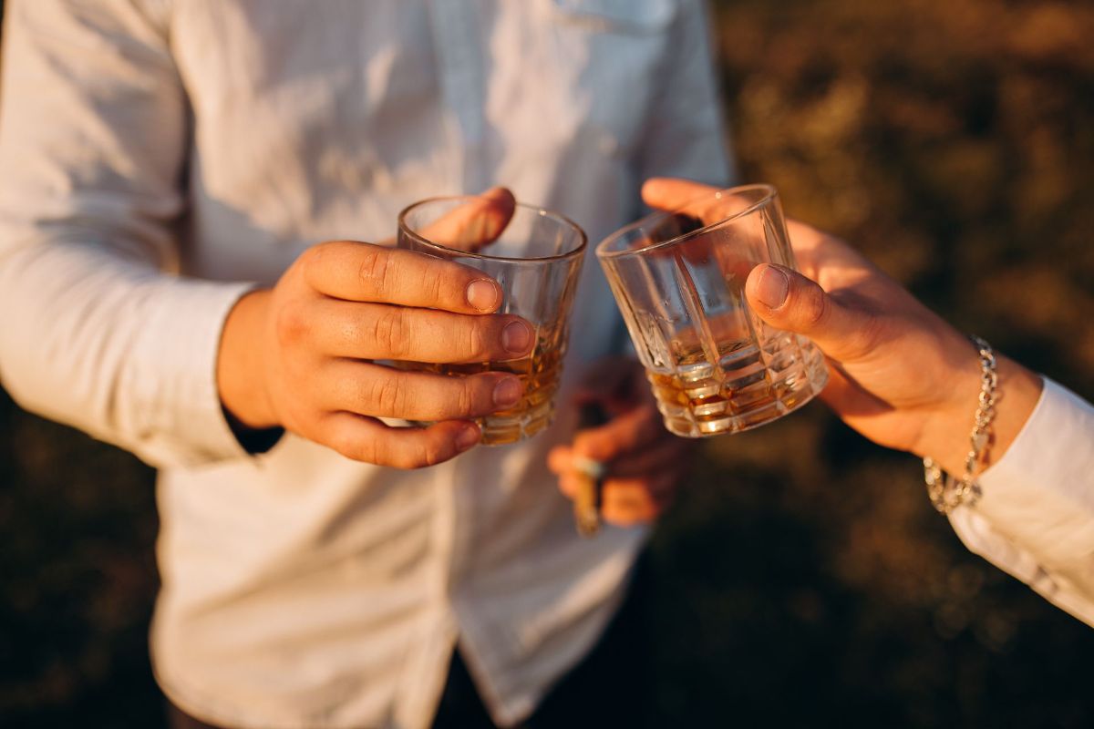 A man and a woman are toasting with two glasses of whiskey.