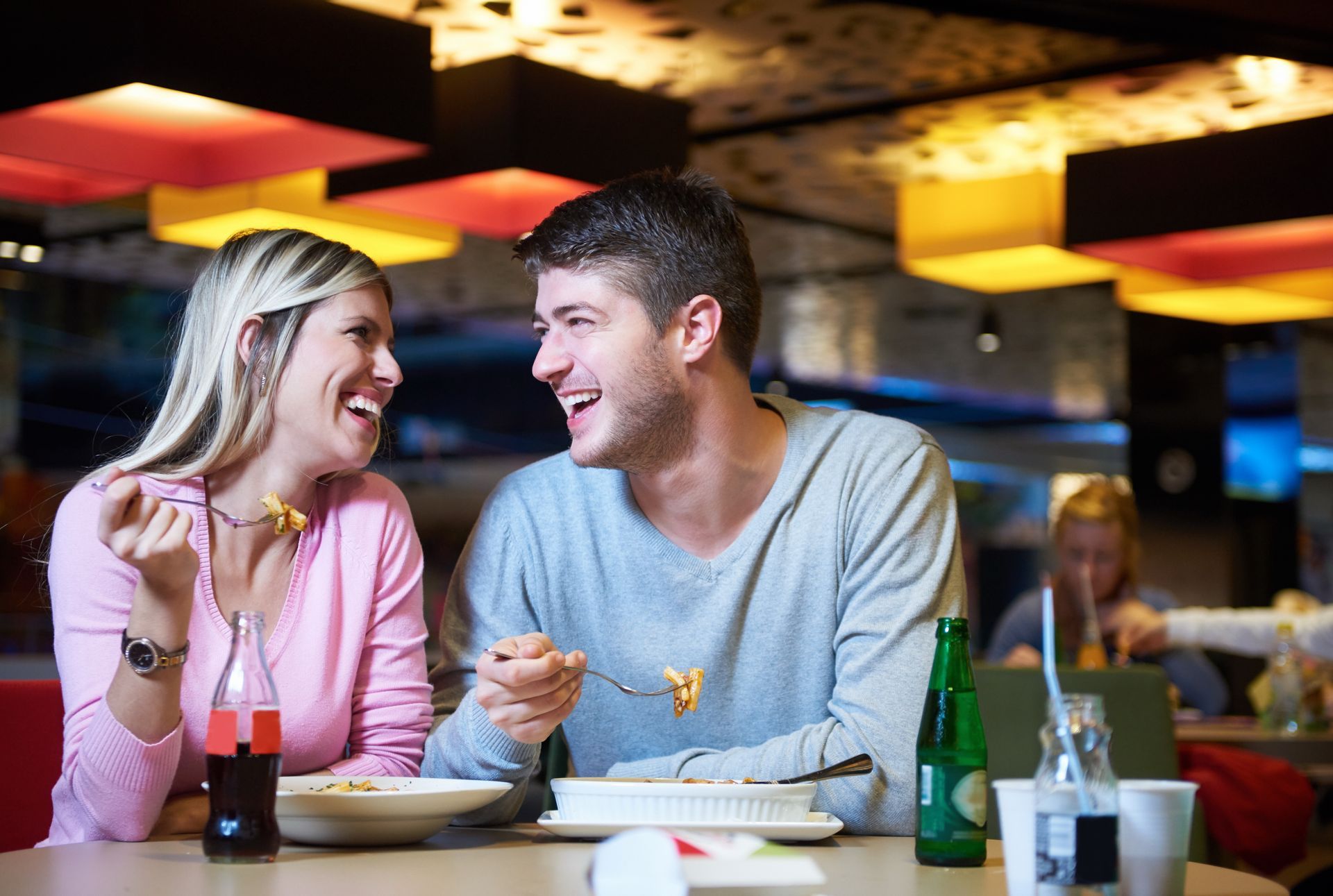 A man and a woman are sitting at a table in a restaurant eating food.