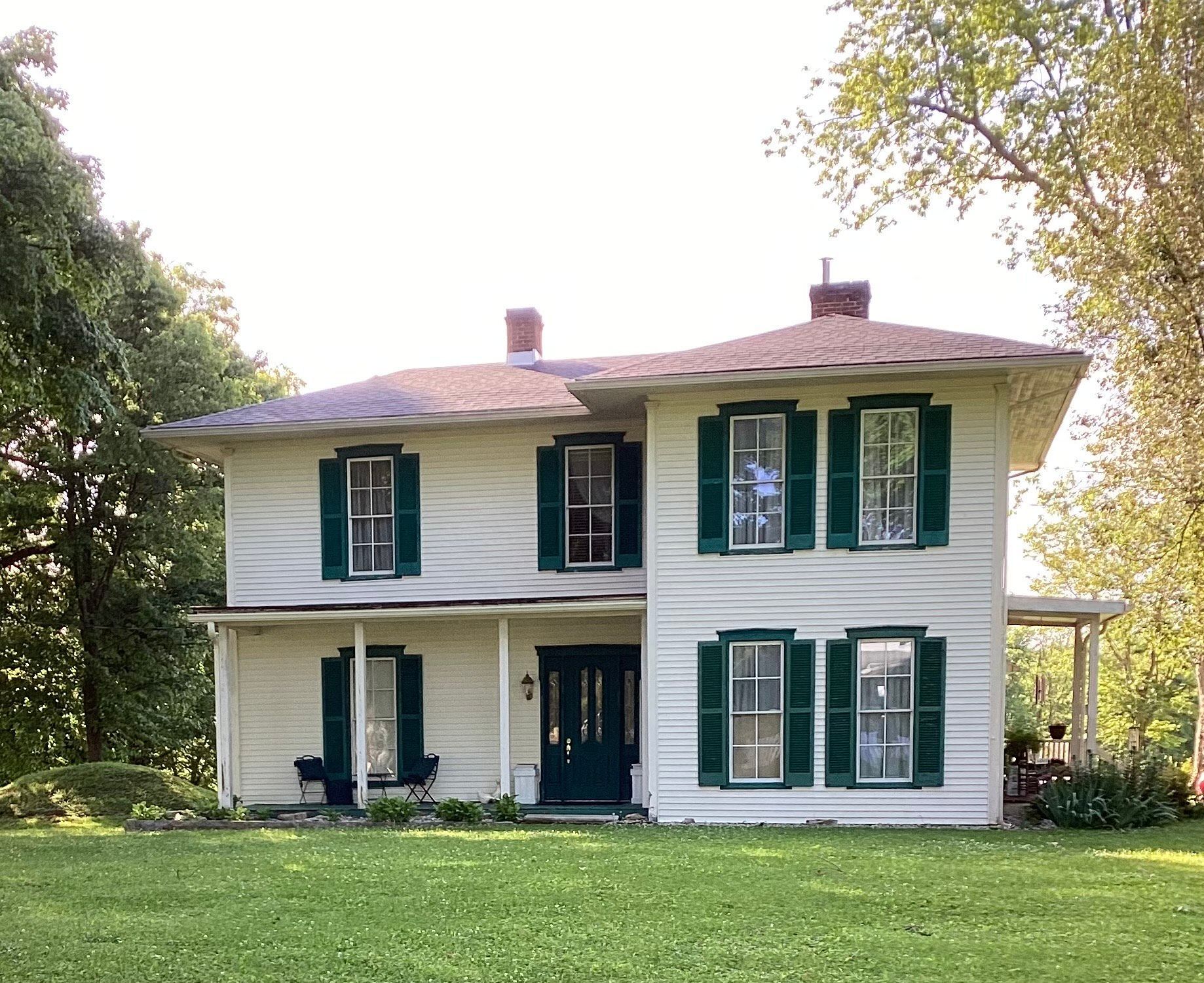 A white house with green shutters and a porch