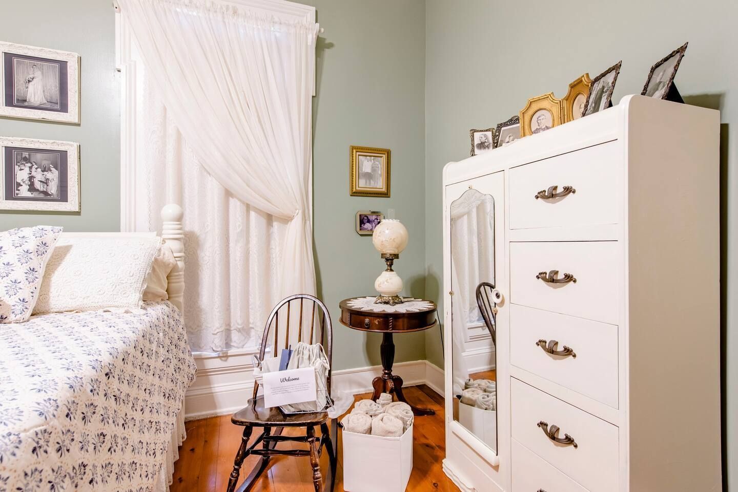 A bedroom with a bed , dresser , chair and table.