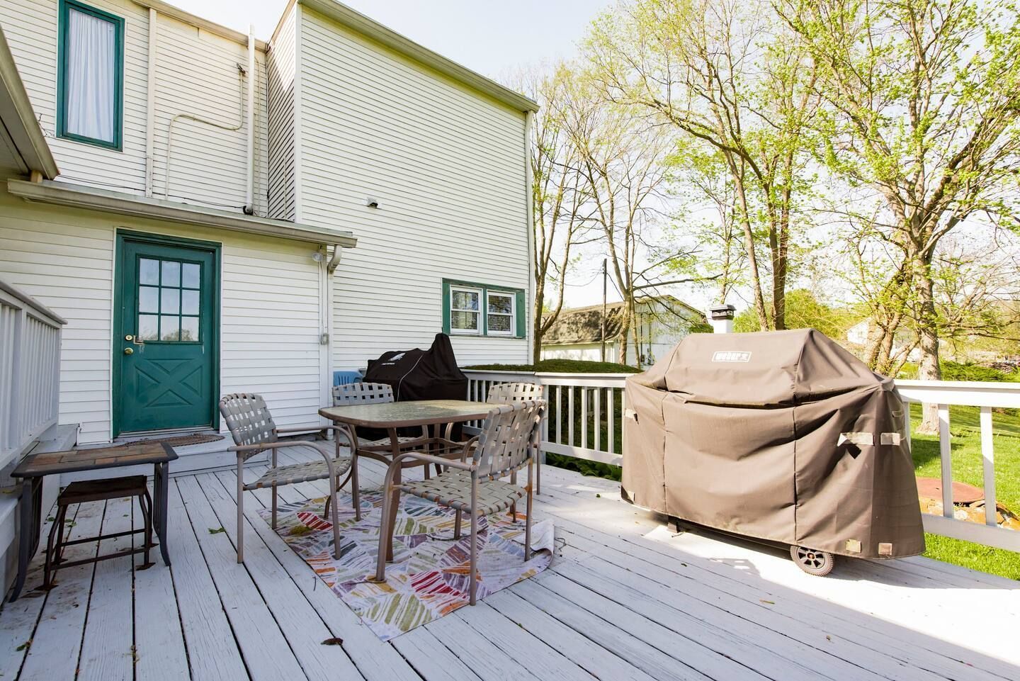 A white deck with a table and chairs and a grill.