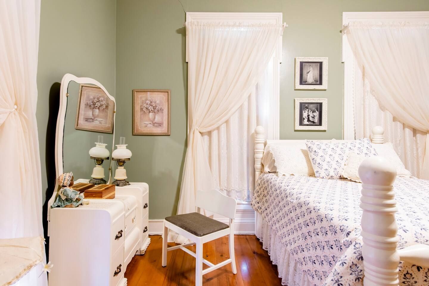 A bedroom with a canopy bed , dresser , mirror and stool.