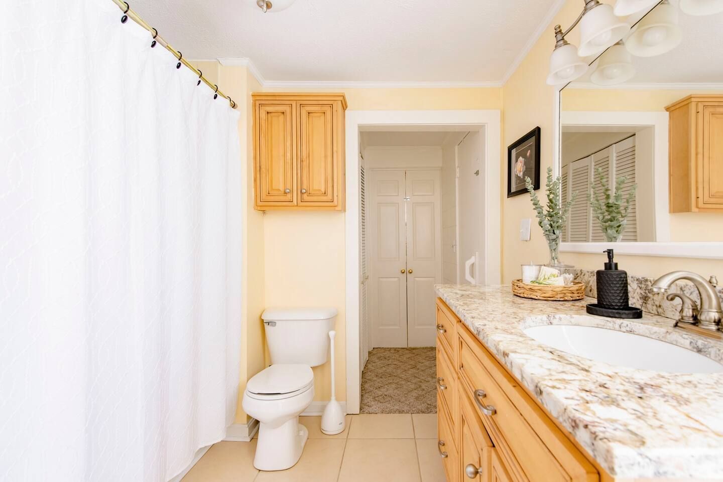 A bathroom with a toilet , sink and mirror.