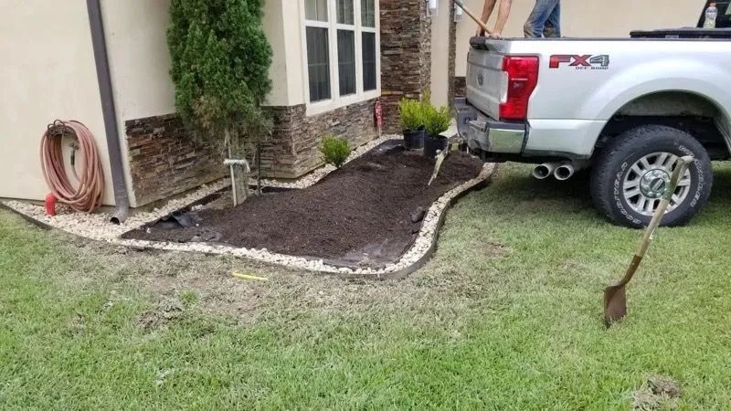 Landscaping with mulch, gravel border, near a house and truck.