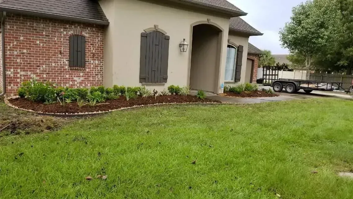 A house with a brick and stucco exterior, green lawn, and trailer parked outside.