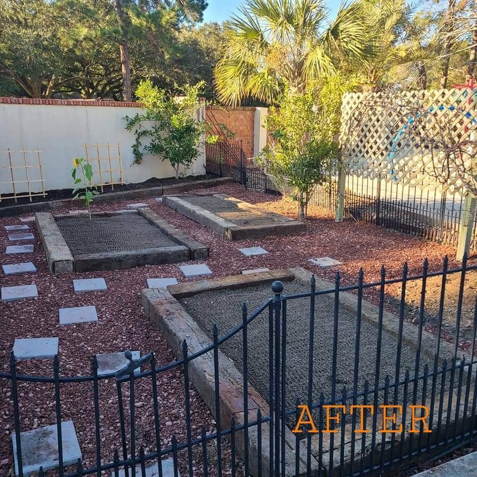 Garden with three raised beds, stepping stones, and mulch, behind a black fence.