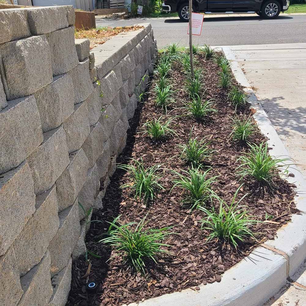 Retaining wall with a planted garden bed along a curb.