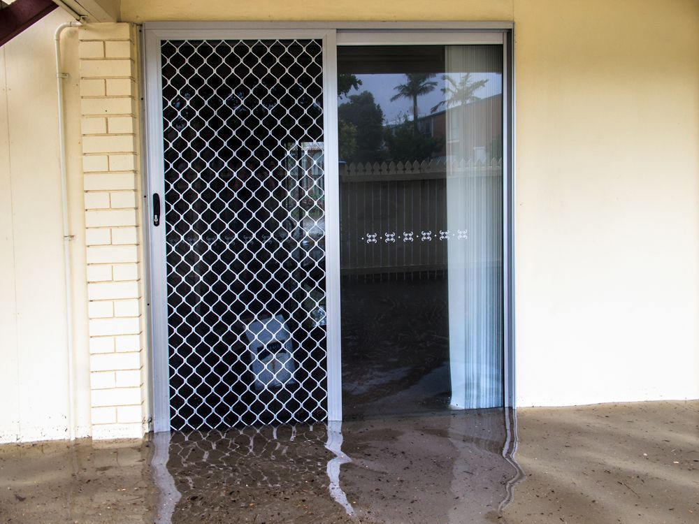 Sliding glass door with security screen, reflecting a flooded porch. — Moore Park Beach Glass & Security in Bargara, QLD