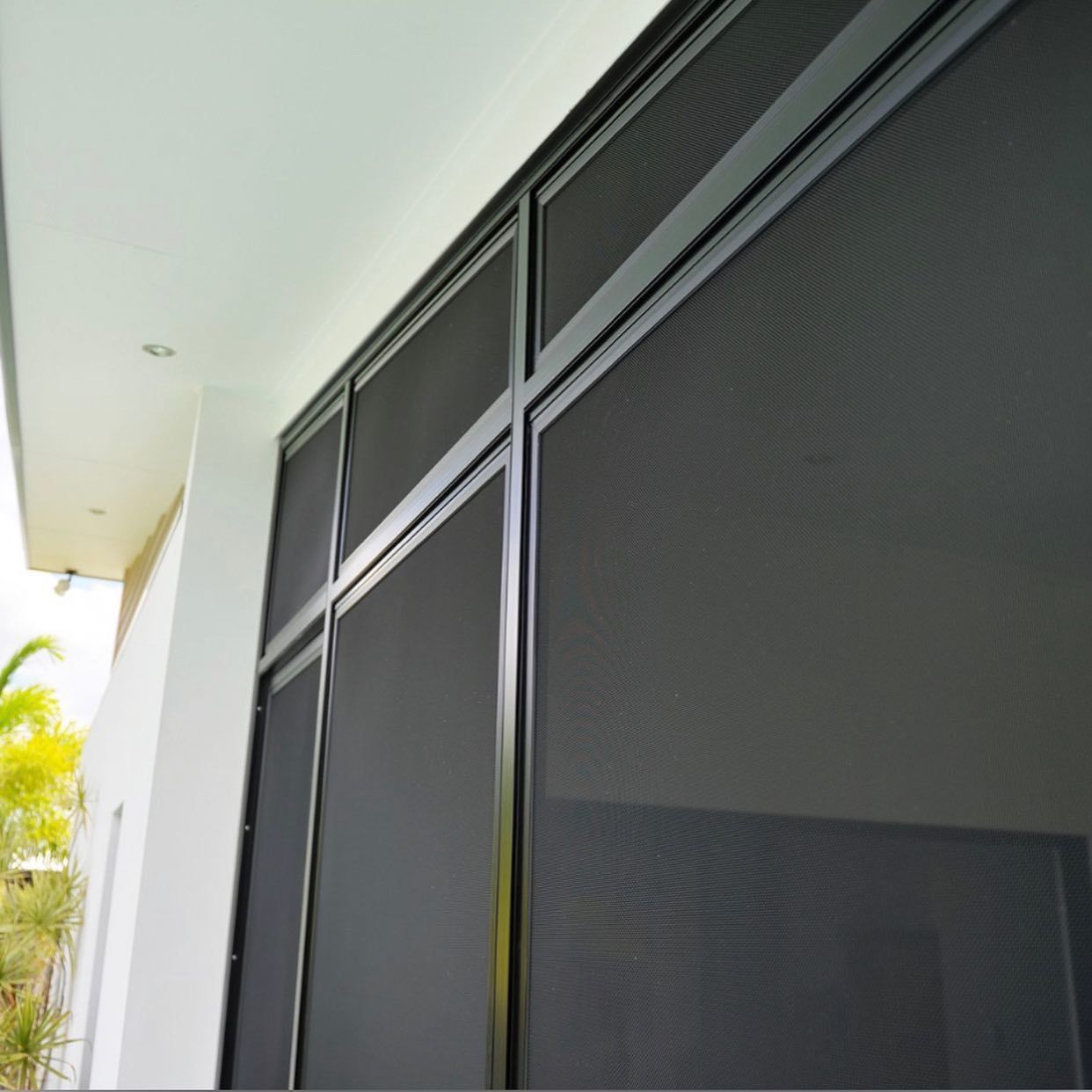 Black screened windows framed with black metal on a white building. — Moore Park Beach Glass & Security in Childers, QLD