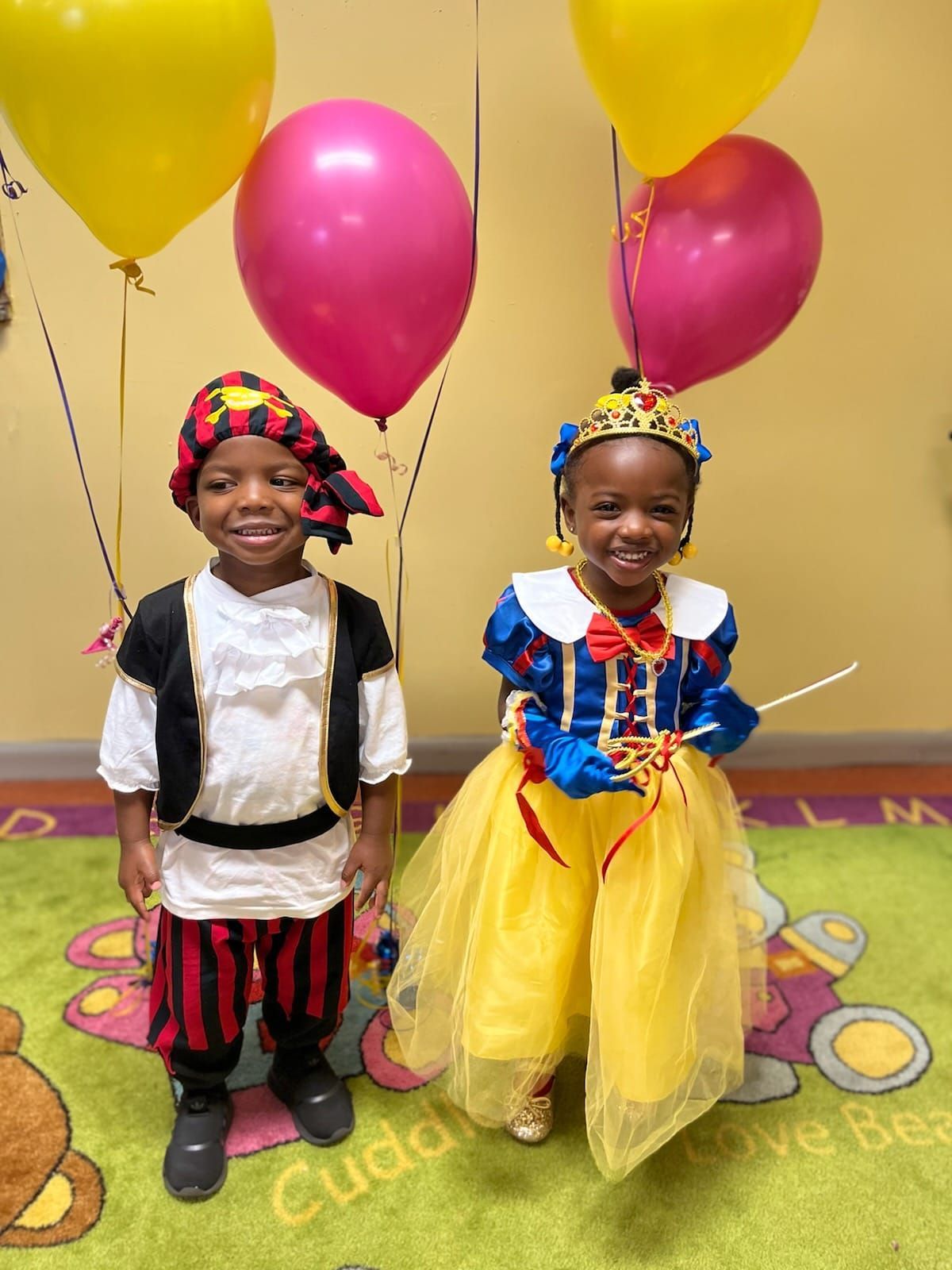a boy and a girl in costumes are standing next to each other in front of balloons .