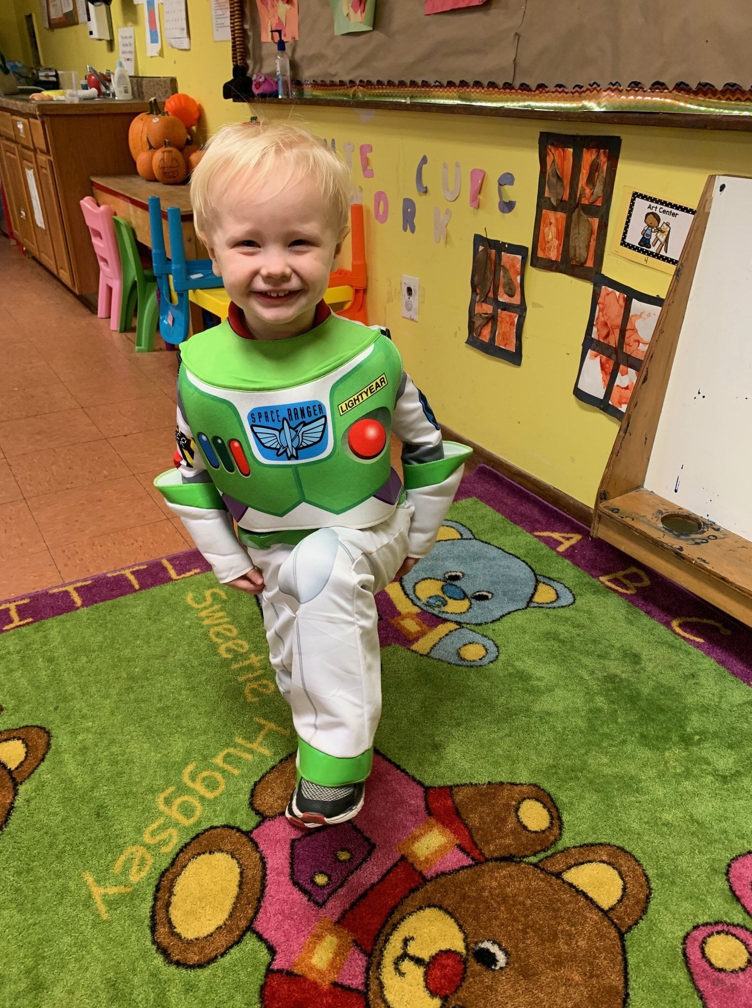 a young boy in a buzz lightyear costume is standing on a rug .