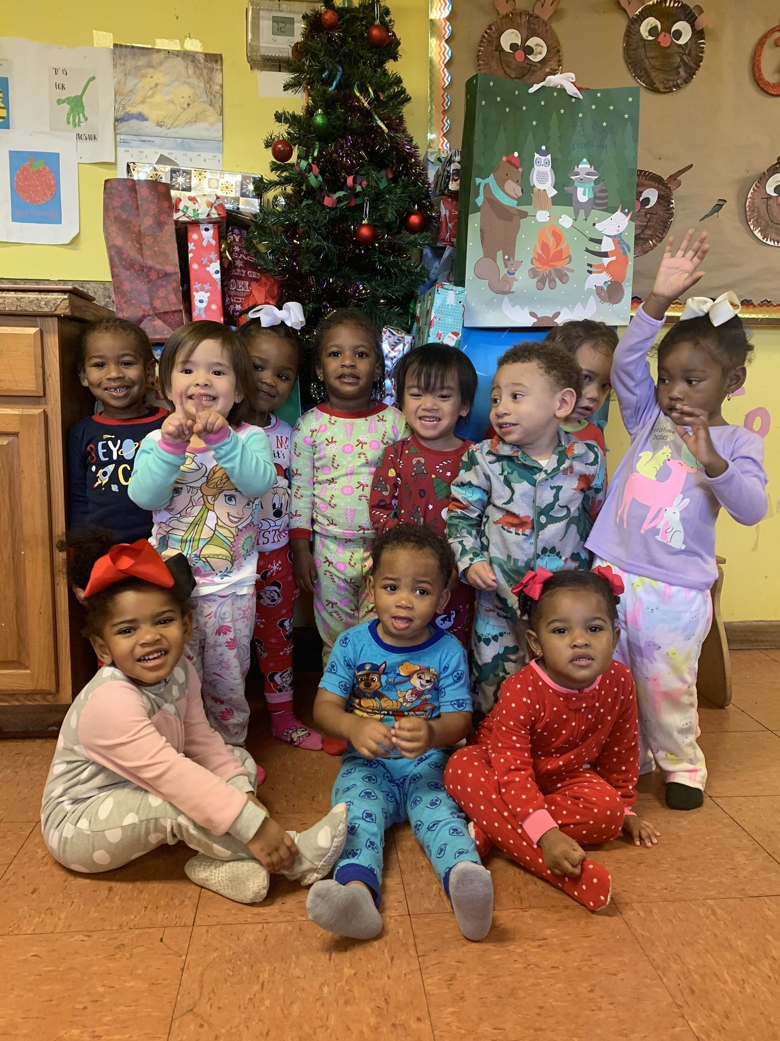 a group of children in pajamas are posing for a picture in front of a christmas tree .
