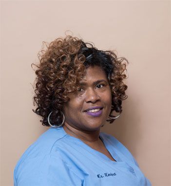 a woman with curly hair and hoop earrings is wearing a blue scrub top .