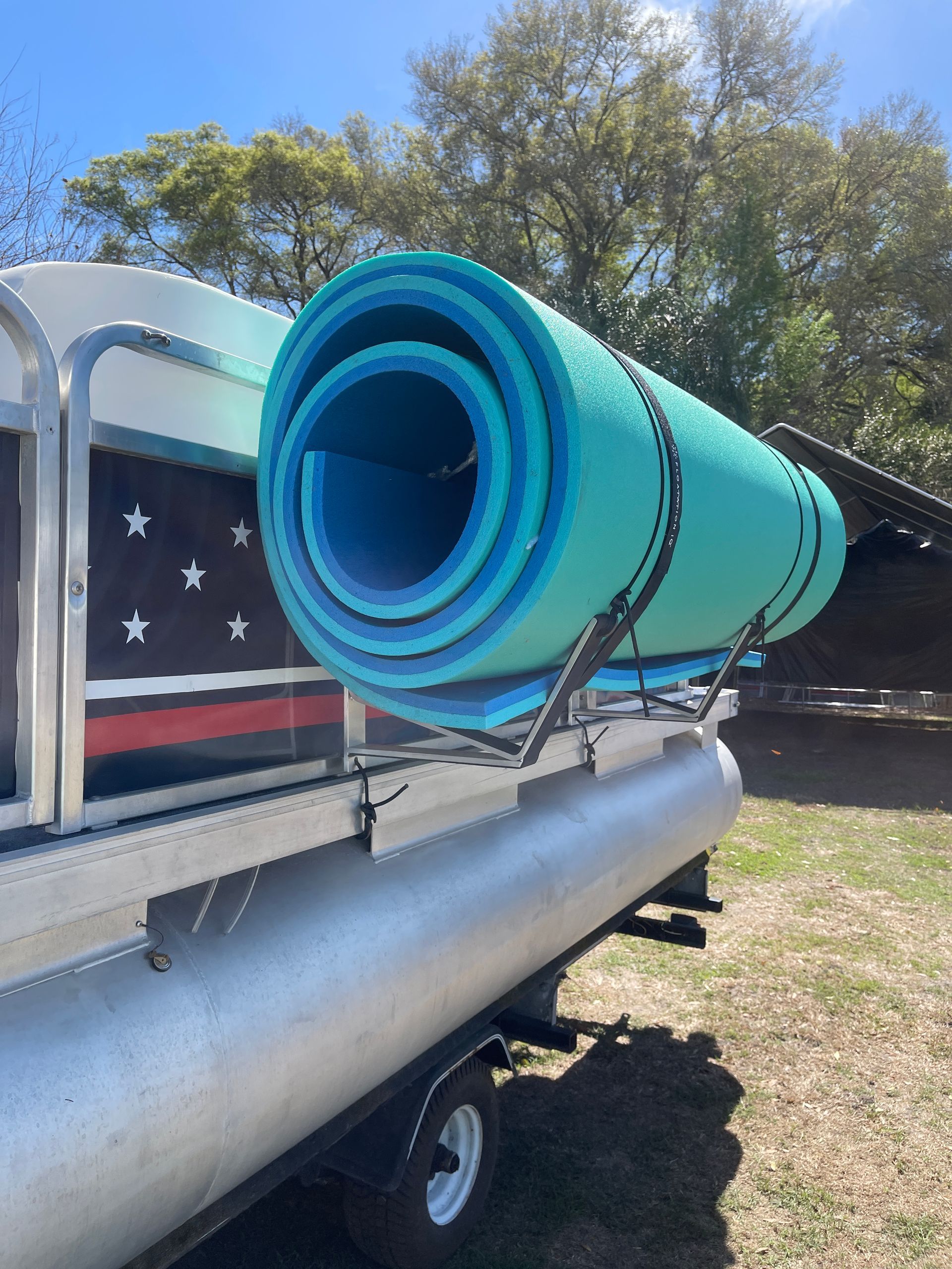 Turquoise pontoon boat water mat solution rolled on a trailer, labeled “Patent Pending Design”