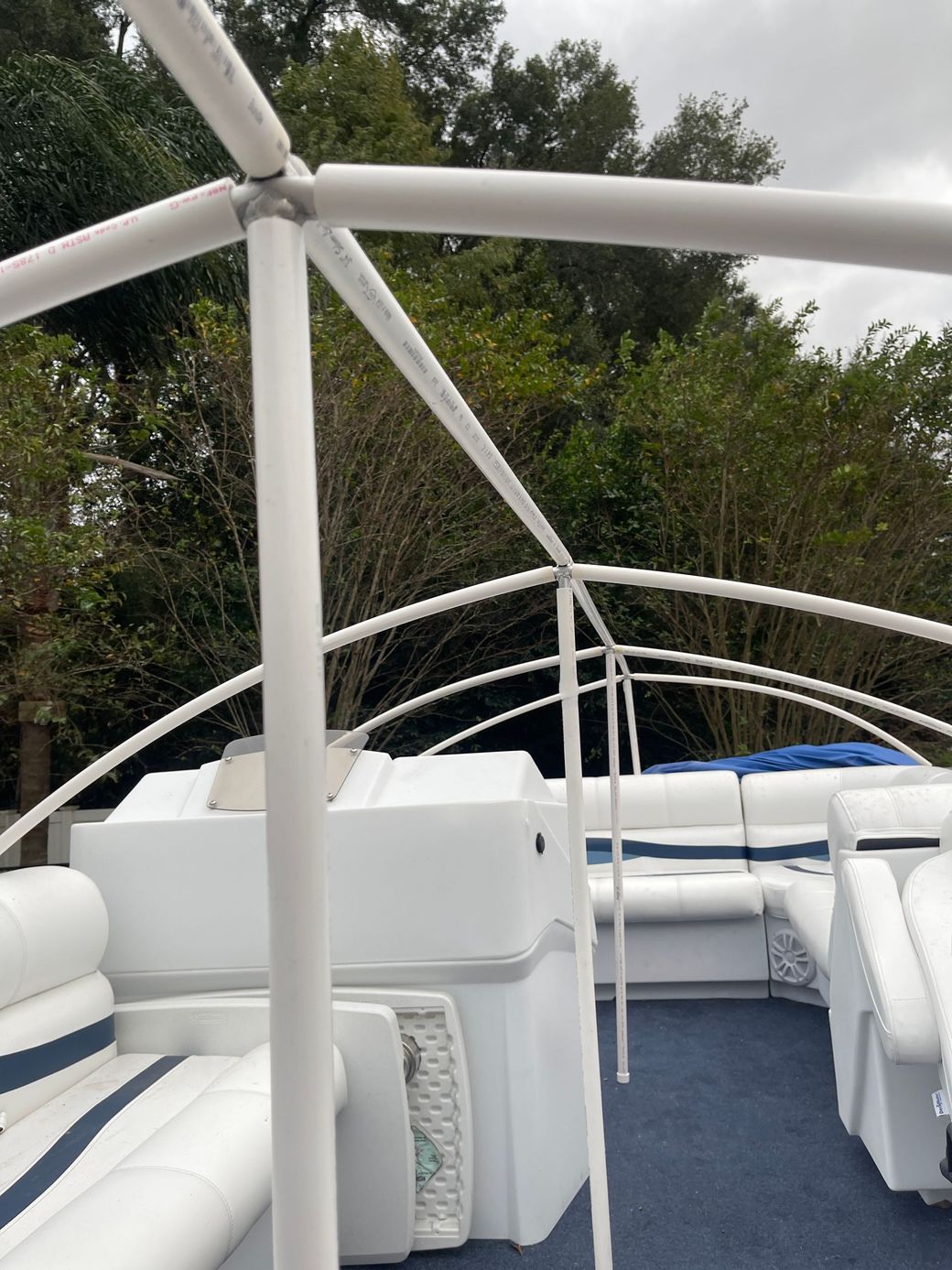 Pontoon Boat ULTIMATE Canvas Solution Arches and Dome canopy frame and seating under an overcast sky.
