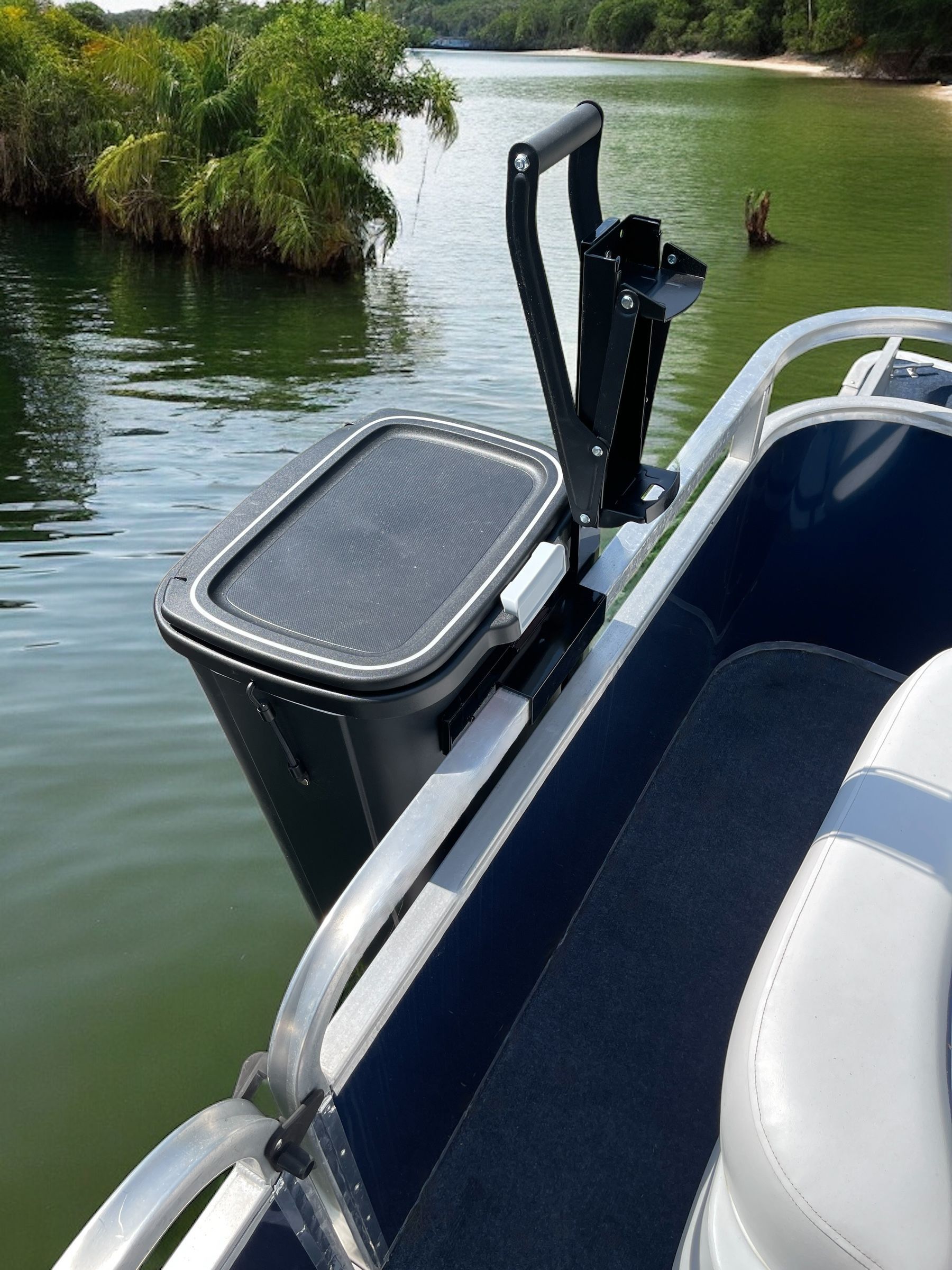 Pontoon Boat Garbage Can with a can crusher mounted on a railing beside calm water and green shoreline.