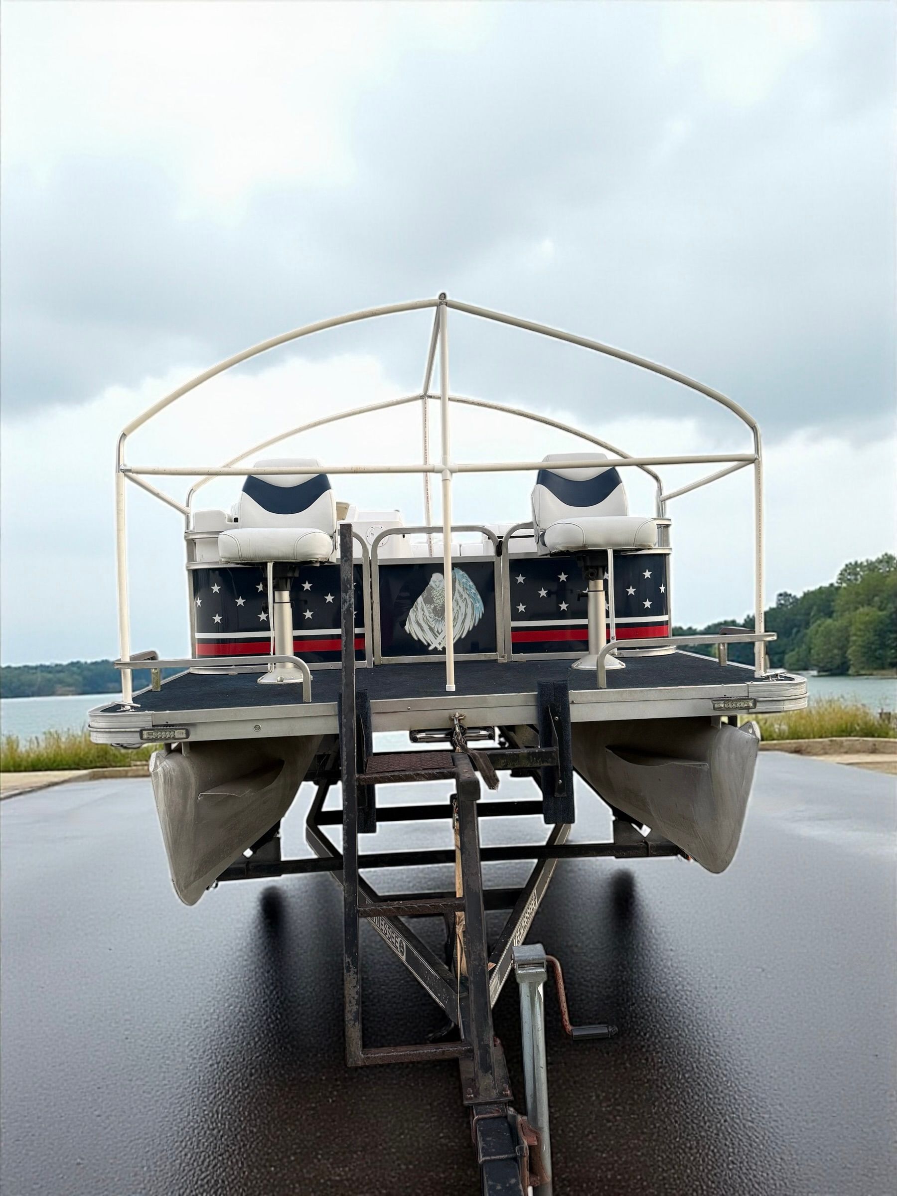 Front view of a boat on a trailer with twin outboard motors on a wet road near water