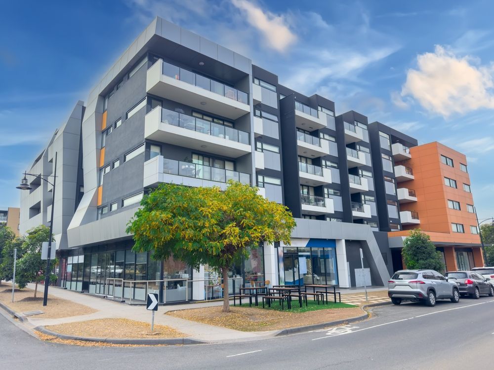 A large apartment building with cars parked in front of it.