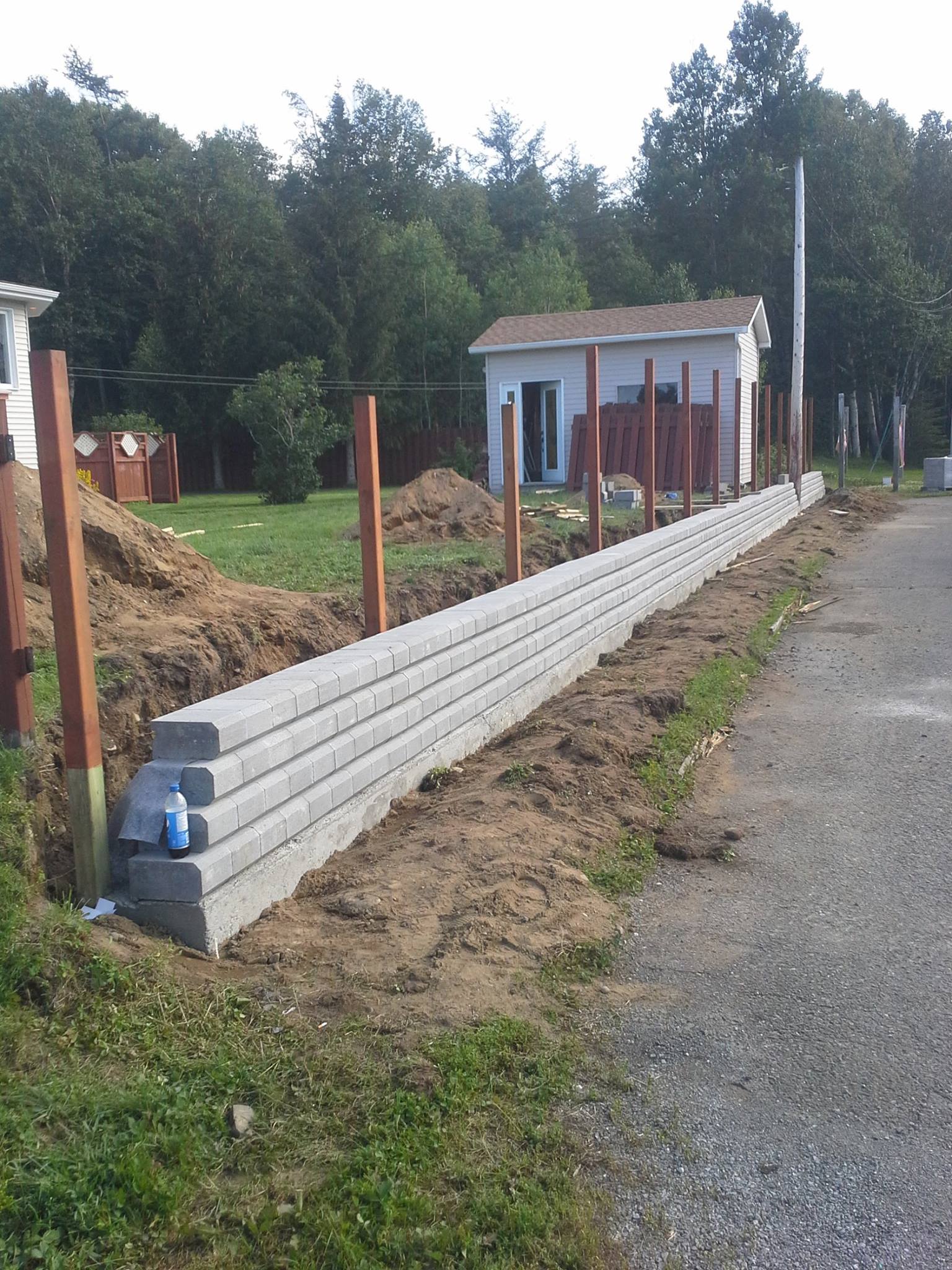 Un mur de béton est en construction à côté d'une route de gravier