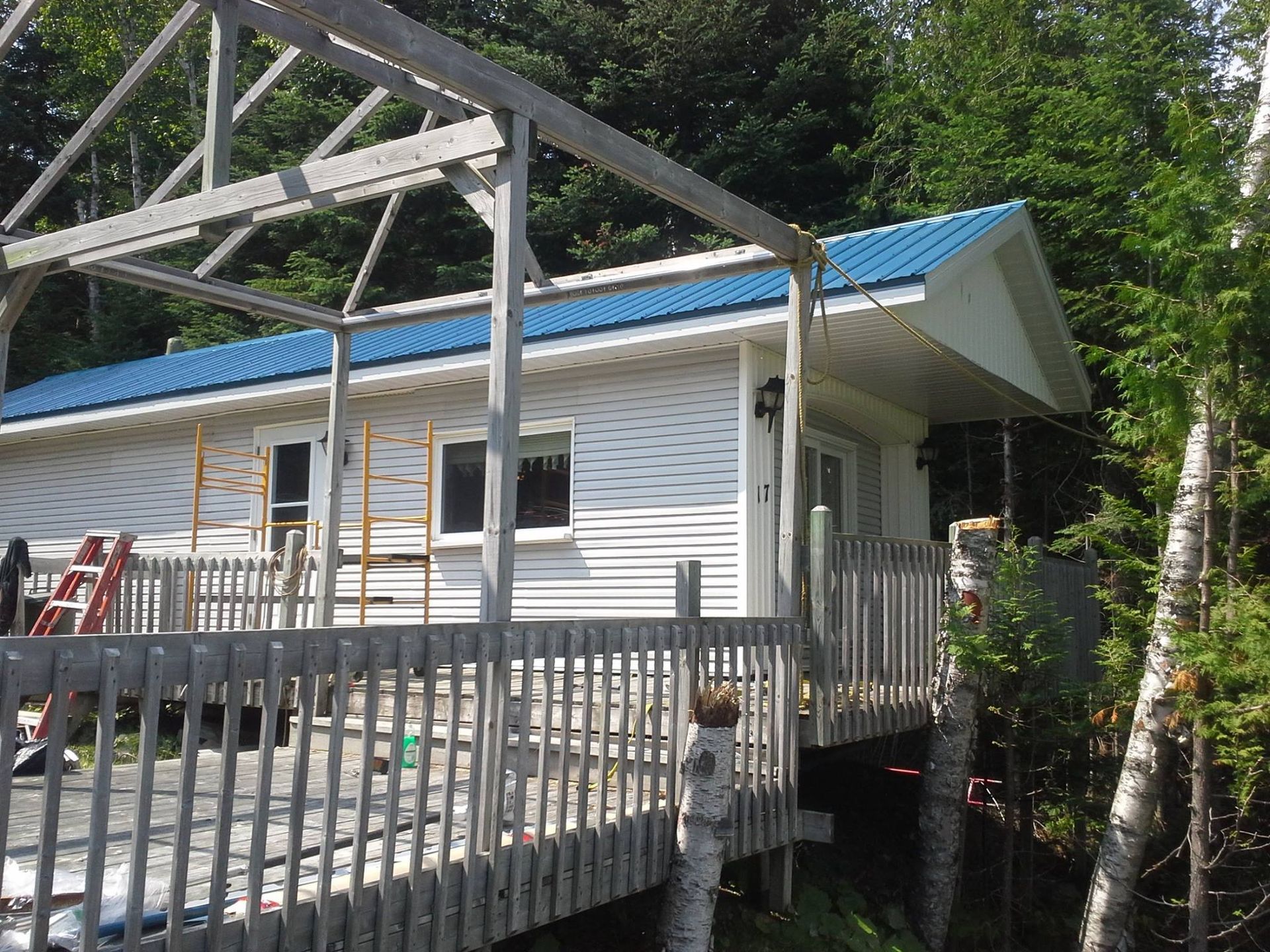 Une maison blanche avec un toit bleu et une terrasse en bois