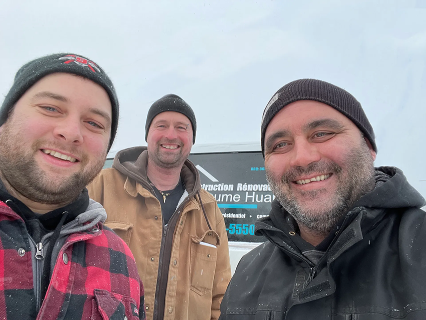 Trois hommes posent pour une photo devant une camionnette.