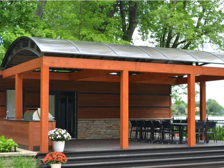 Un gazebo en bois avec un toit en métal et une table et des chaises en dessous