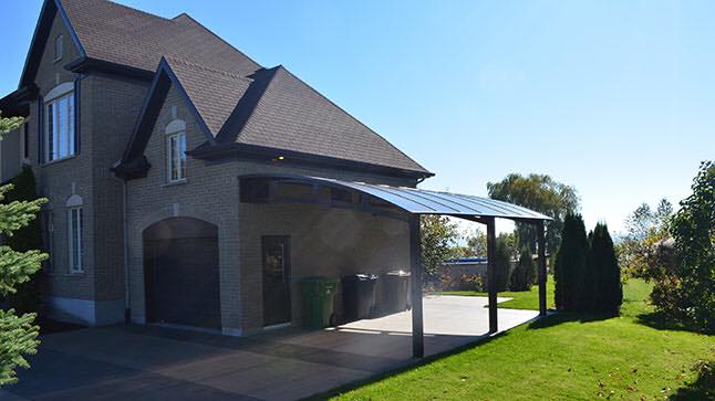 Une grande maison en briques avec un abri voiture devant.
