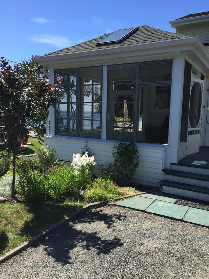 Une maison blanche avec un porche grillagé donnant sur un plan d'eau.