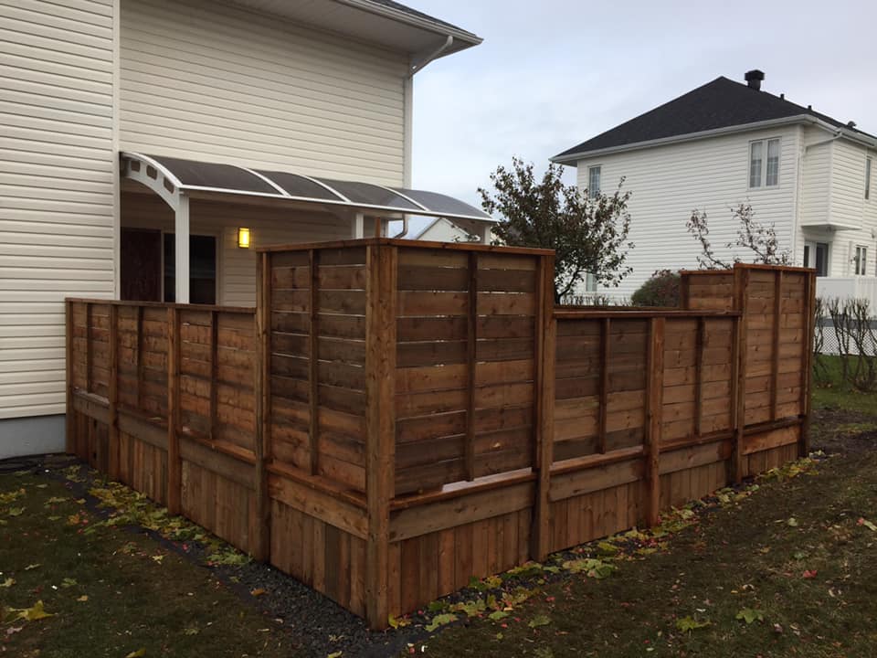 Une clôture en bois se trouve devant une maison blanche