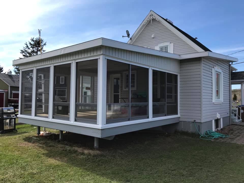Une maison avec un porche grillagé sur le côté.