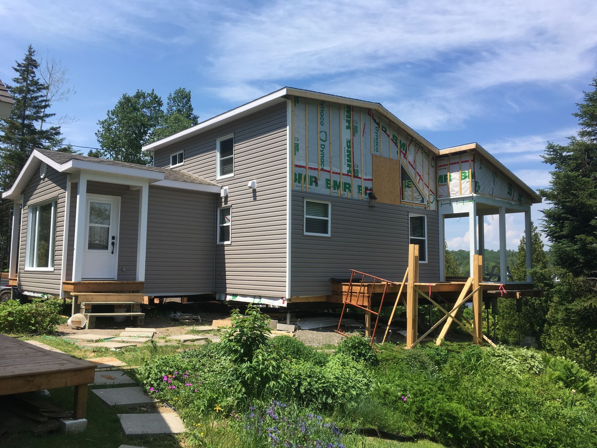 Une maison est en construction sur une colline avec beaucoup d'arbres en arrière-plan.