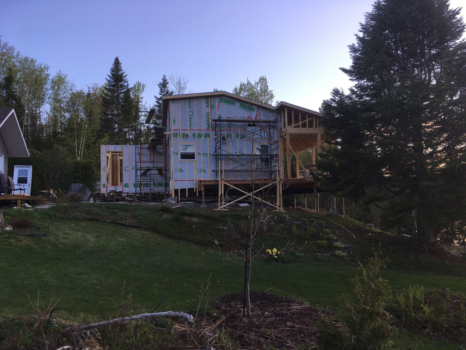 Une maison est en construction au milieu d'un champ verdoyant.