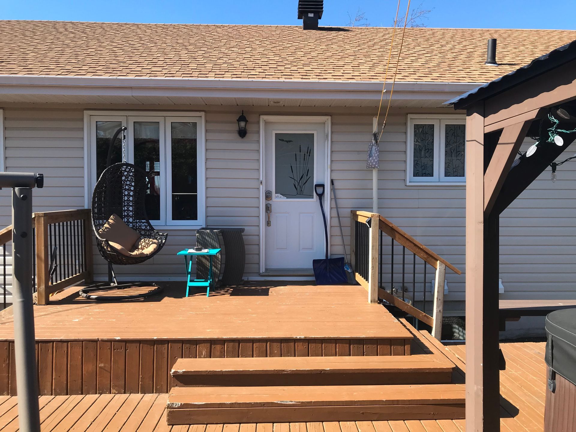 Une maison avec une terrasse en bois et des escaliers menant à la porte d'entrée.