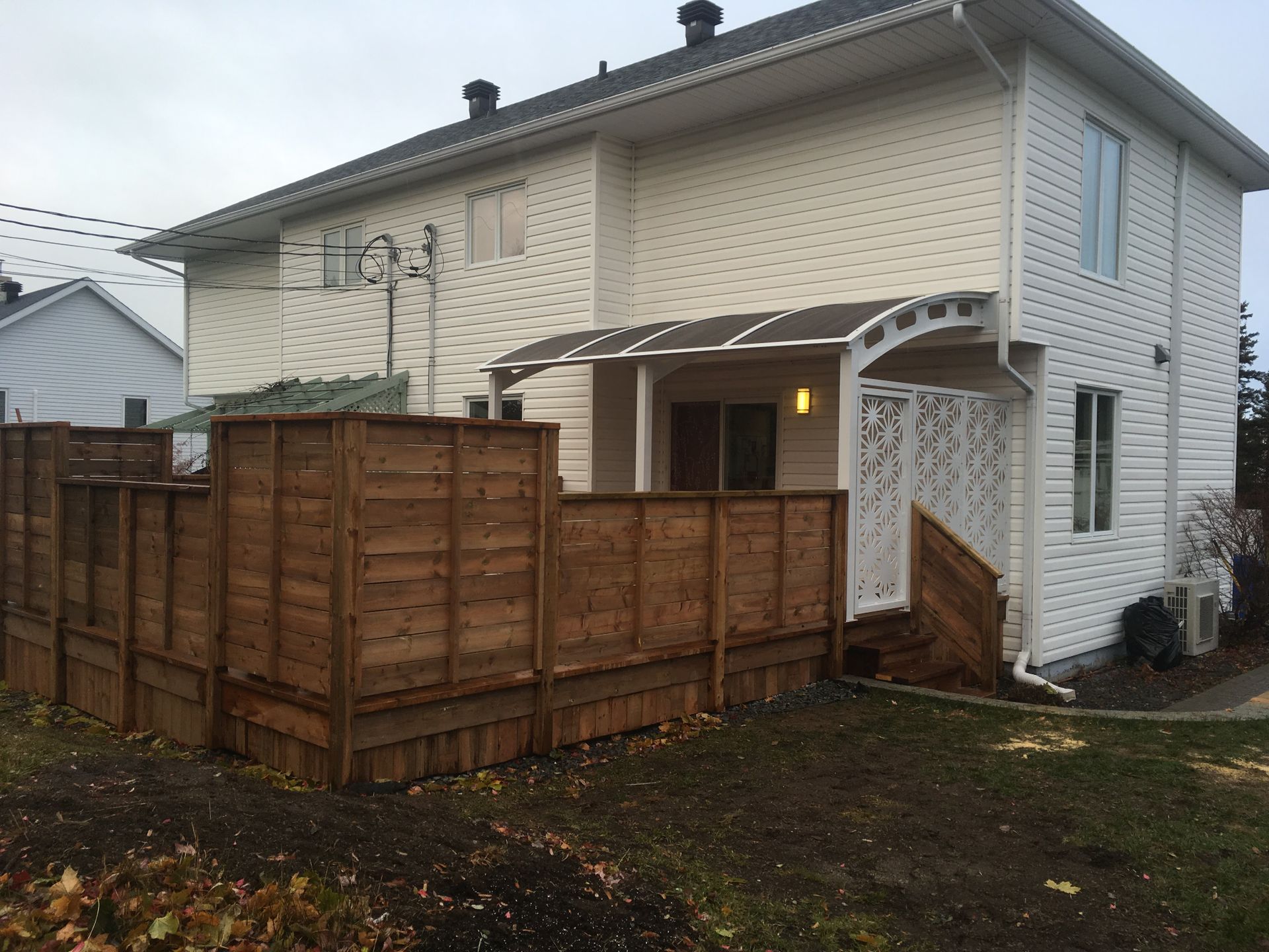 Une maison blanche avec une clôture en bois devant elle
