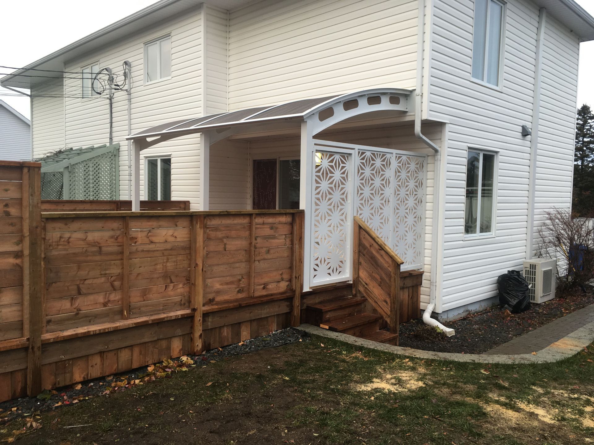 Une maison blanche avec une clôture en bois devant.