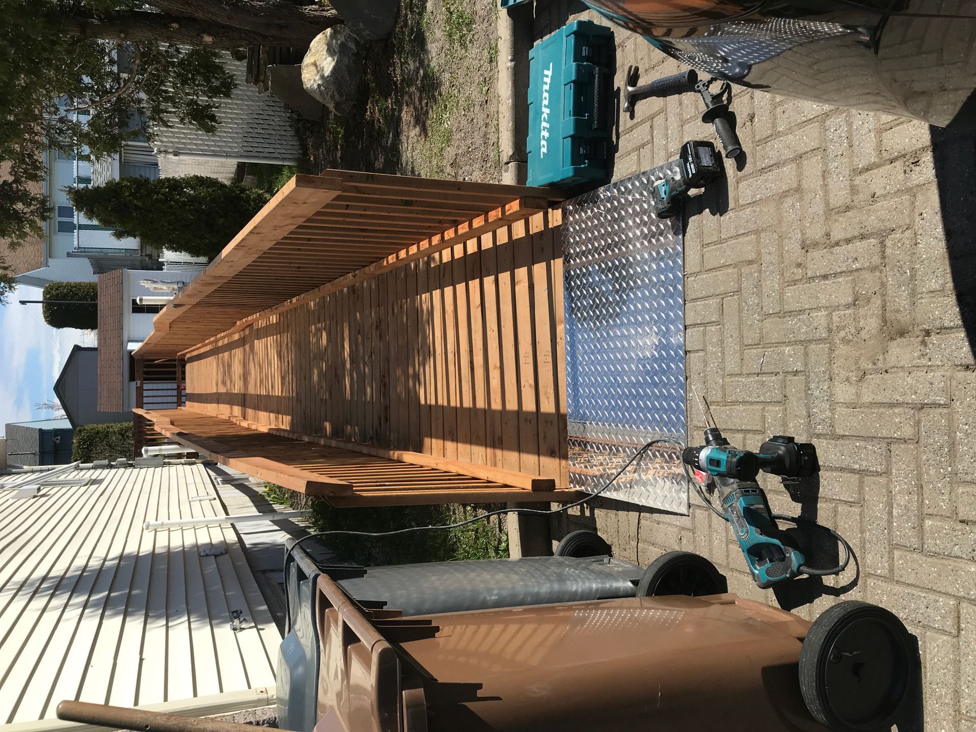 Un outil Makita est posé sur un trottoir en briques à côté d'un banc en bois.