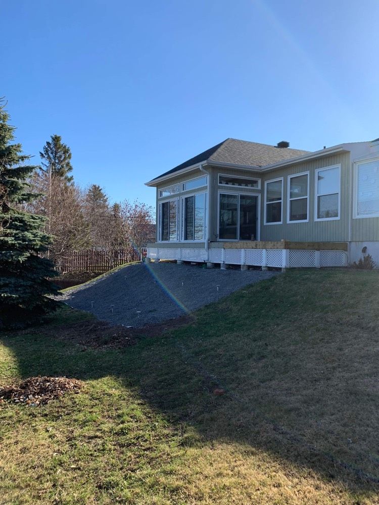 Une grande maison avec beaucoup de fenêtres est située au sommet d'une colline herbeuse.