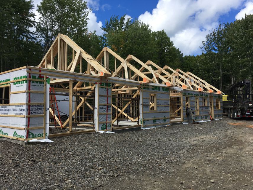 Une grande structure en bois est en cours de construction au milieu d'un champ de terre.