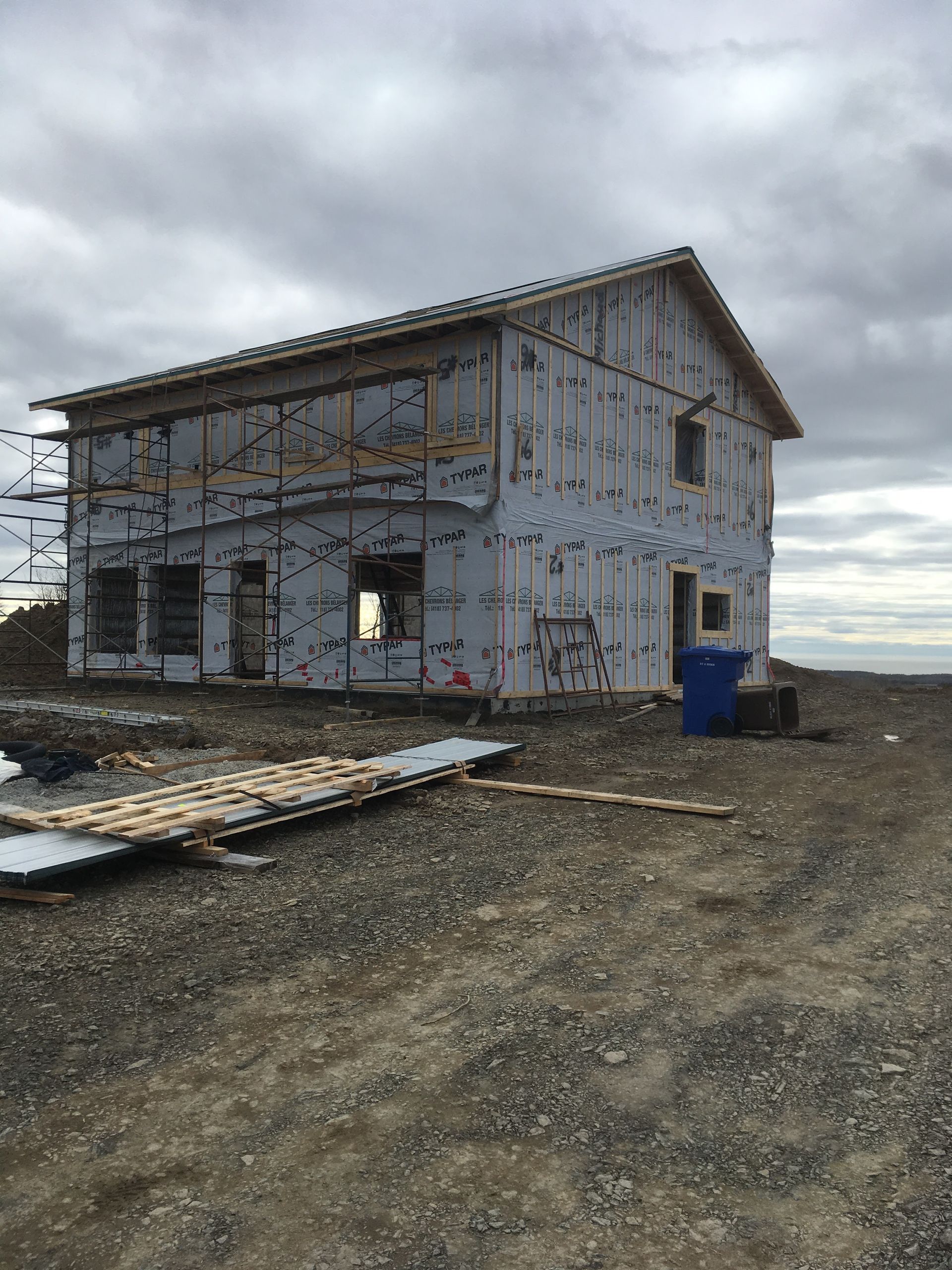 Une maison est en construction au milieu d'un champ de terre.