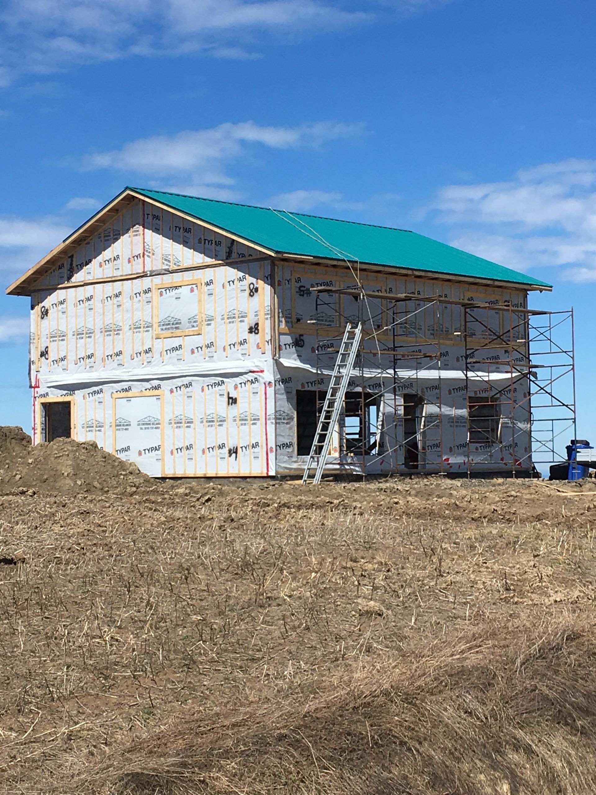 Une maison est en construction dans un champ avec un toit vert.