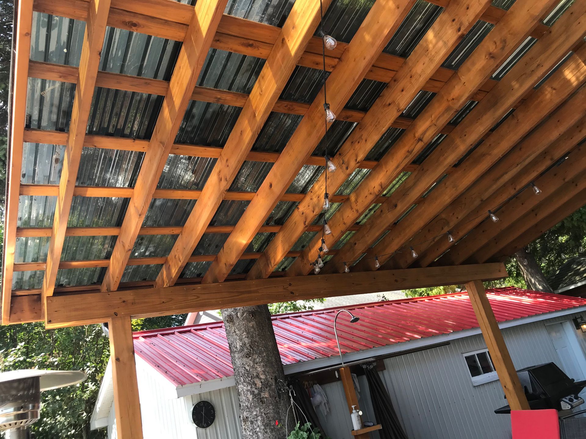 Un toit en bois avec un toit rouge et une maison blanche en arrière-plan