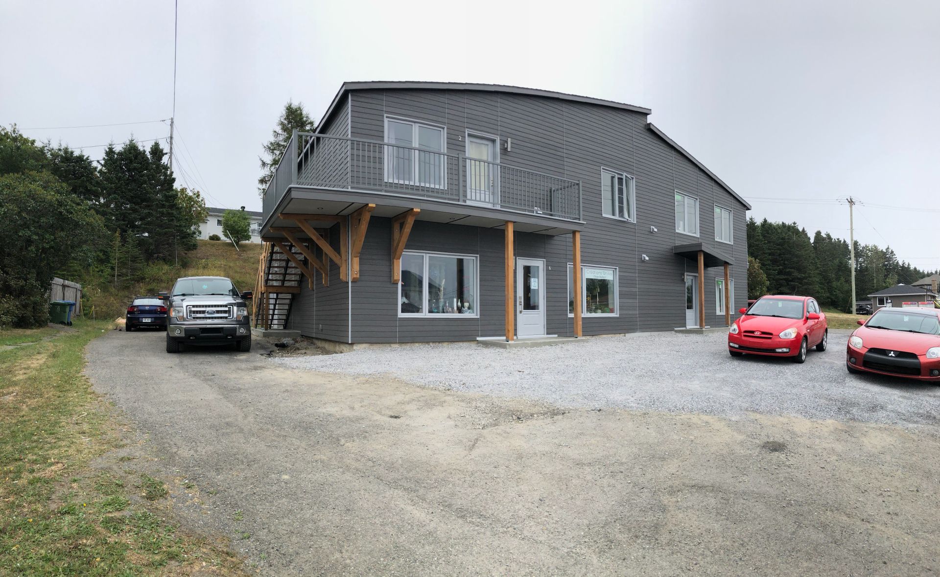 Un grand bâtiment avec des voitures garées devant.